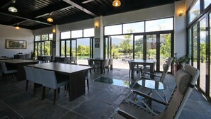 A spacious indoor area with large windows, tables, and chairs arranged for dining or socializing. - Beauty Spring and Harvest B and B (Puli)