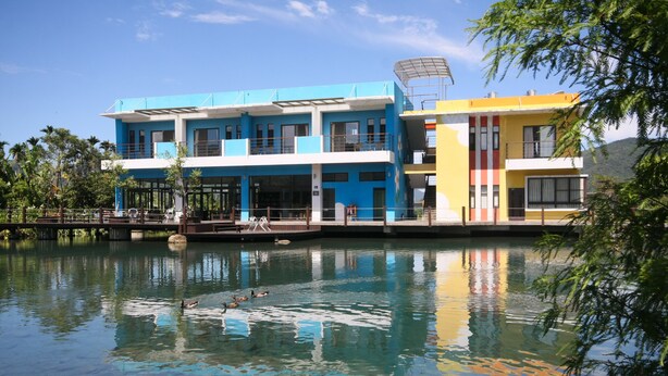 A multi-story building with balconies, a swimming pool, and a bridge. - Beauty Spring and Harvest B and B (Puli)