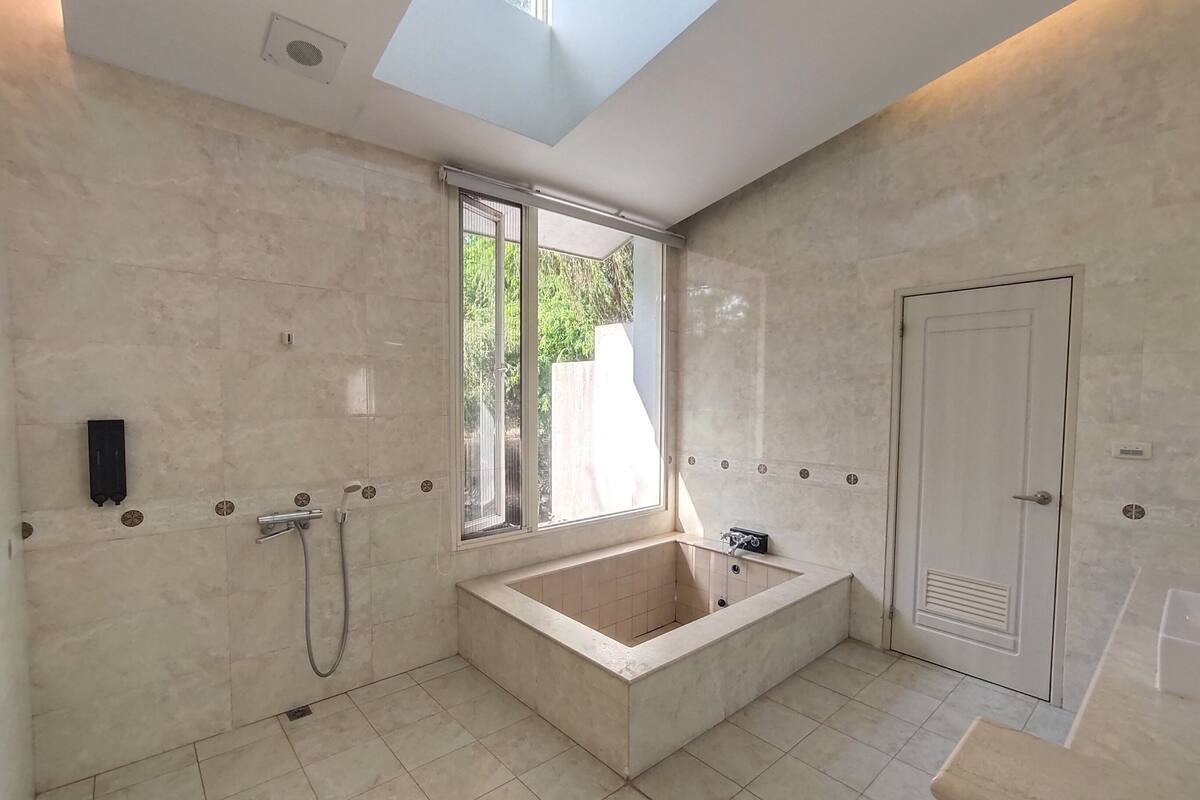 A modern bathroom with a large bathtub, a window, and a skylight.