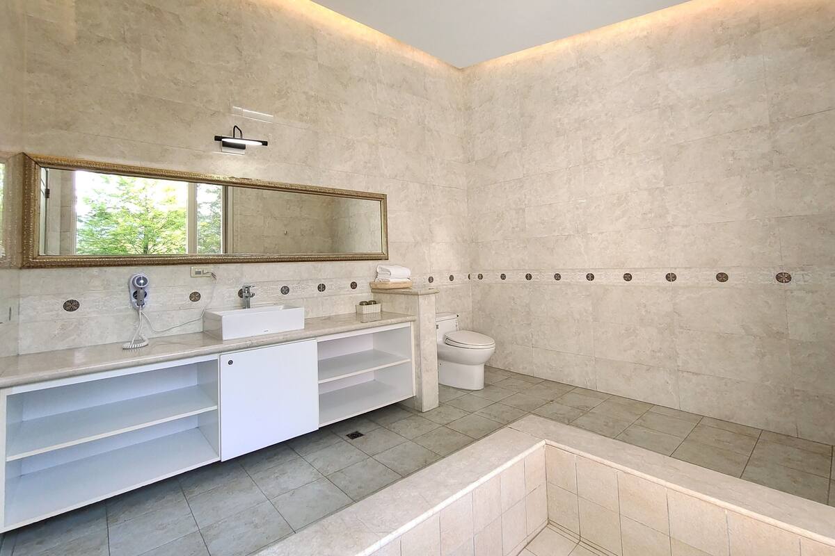 A modern bathroom with a large mirror, white vanity, and a toilet.