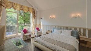 A bedroom with a large bed, two chairs, a nightstand, and a chandelier. - Beauty Spring and Harvest B and B (Puli)