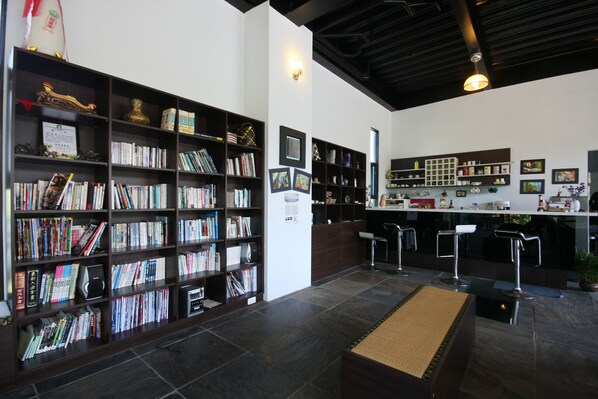 Una biblioteca con estanterías, un mostrador de recepción y una zona de bar.