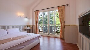 A bedroom with a large bed, a TV, and a sliding glass door leading to an outdoor area. - Beauty Spring and Harvest B and B (Puli)