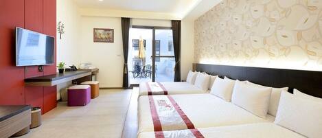 Quarto de hotel com duas camas, televisão, escrivaninha e vista para o exterior.