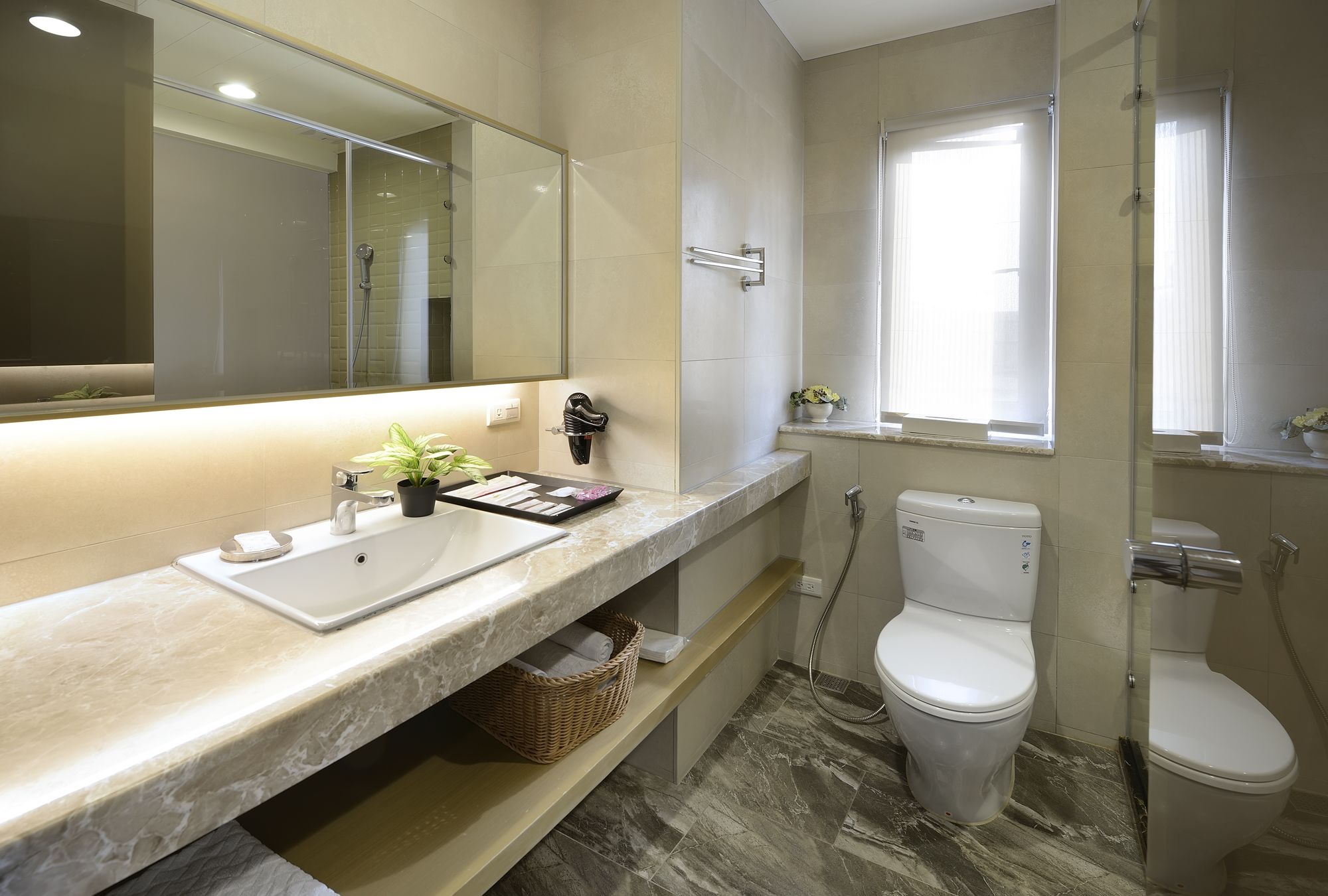 A modern bathroom with a marble sink, a toilet, and a shower.