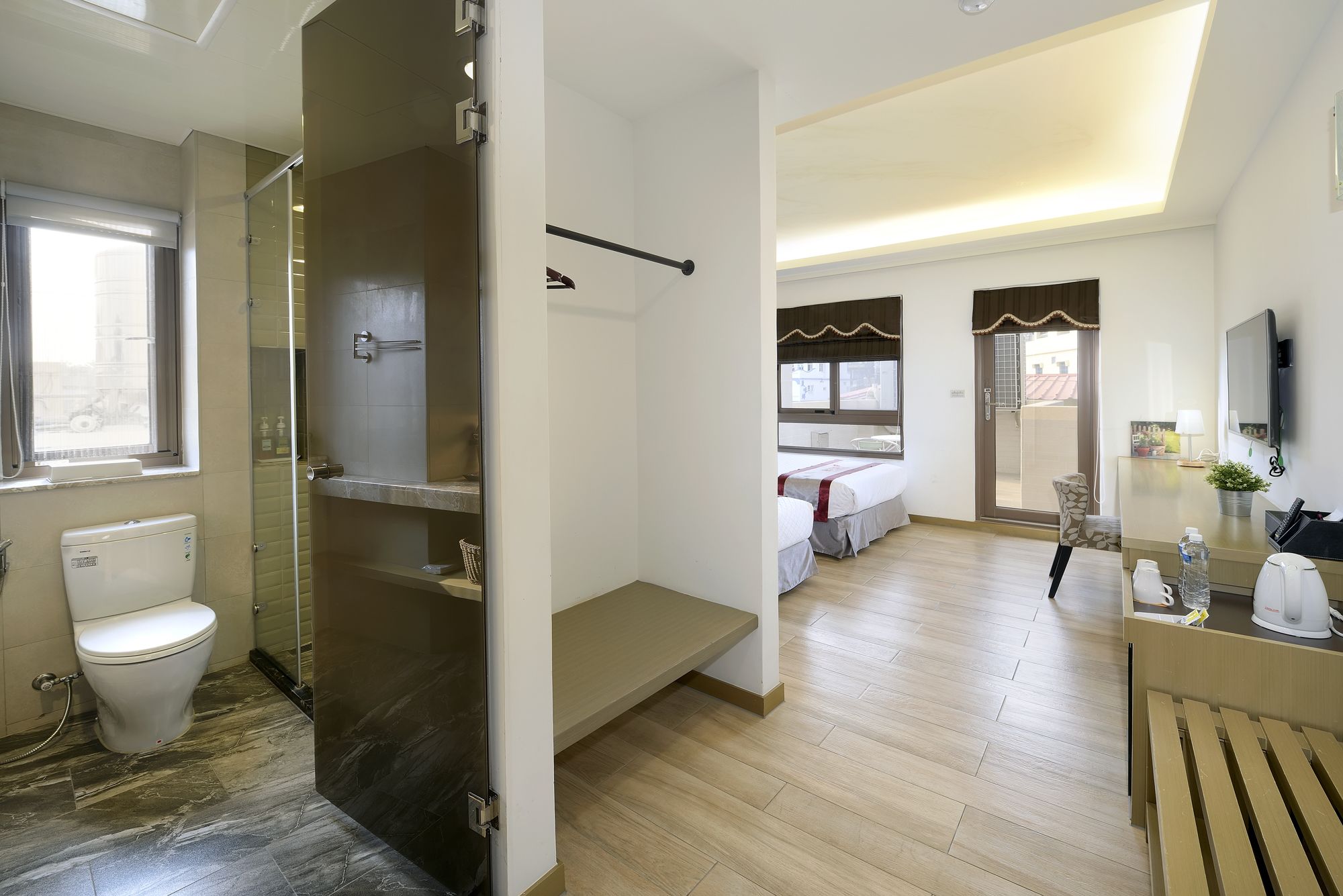 A hotel room with a shower, toilet, and a bed.