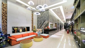 A modern lobby with a sofa, ottomans, and a fireplace.