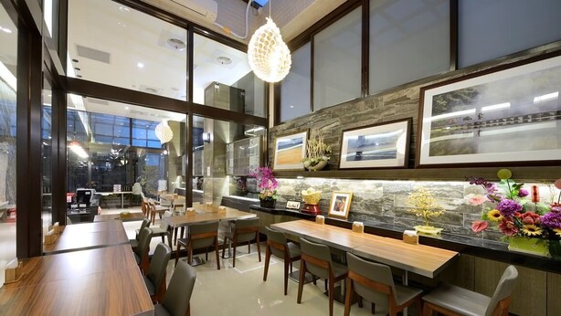 A modern dining area with wooden tables and chairs, a stone backsplash, and framed pictures on the wall.
