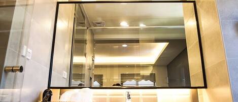 A modern bathroom with a large mirror, a white sink, and a towel rack.