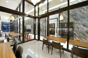 Un comedor moderno con separadores de vidrio, mesas y sillas de madera.