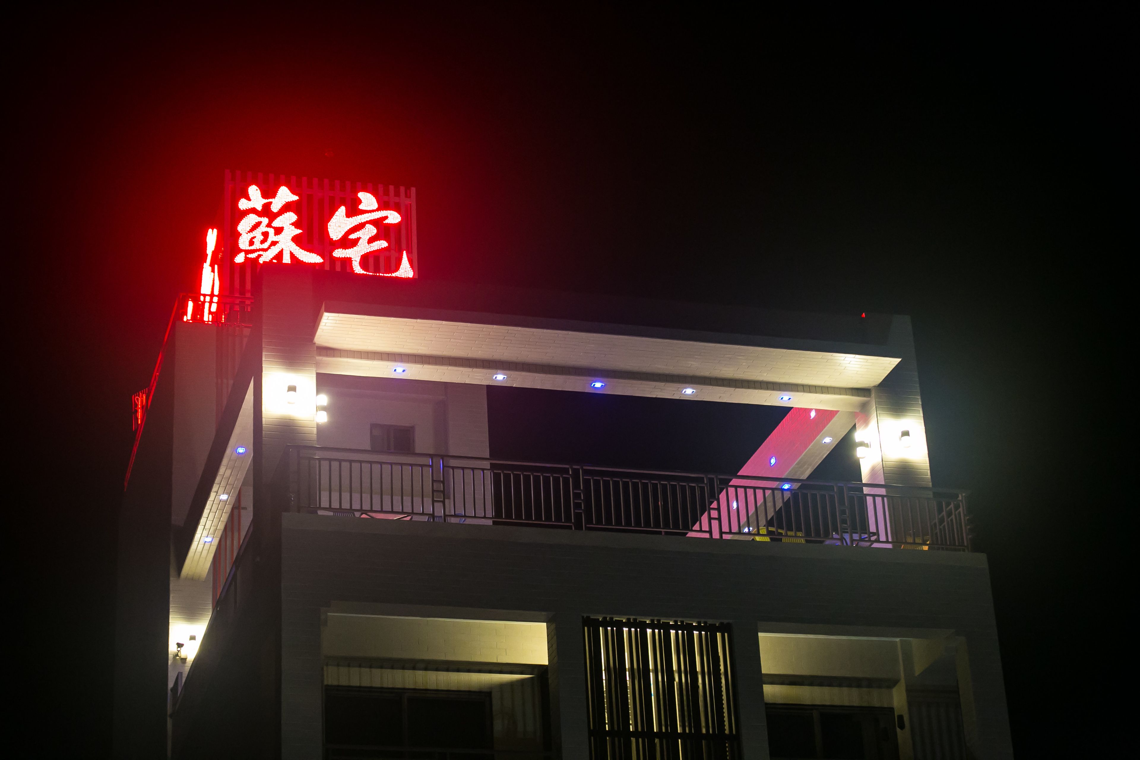 Un edificio con letreros iluminados y un balcón.