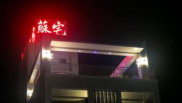 Un edificio con letreros iluminados y un balcón.