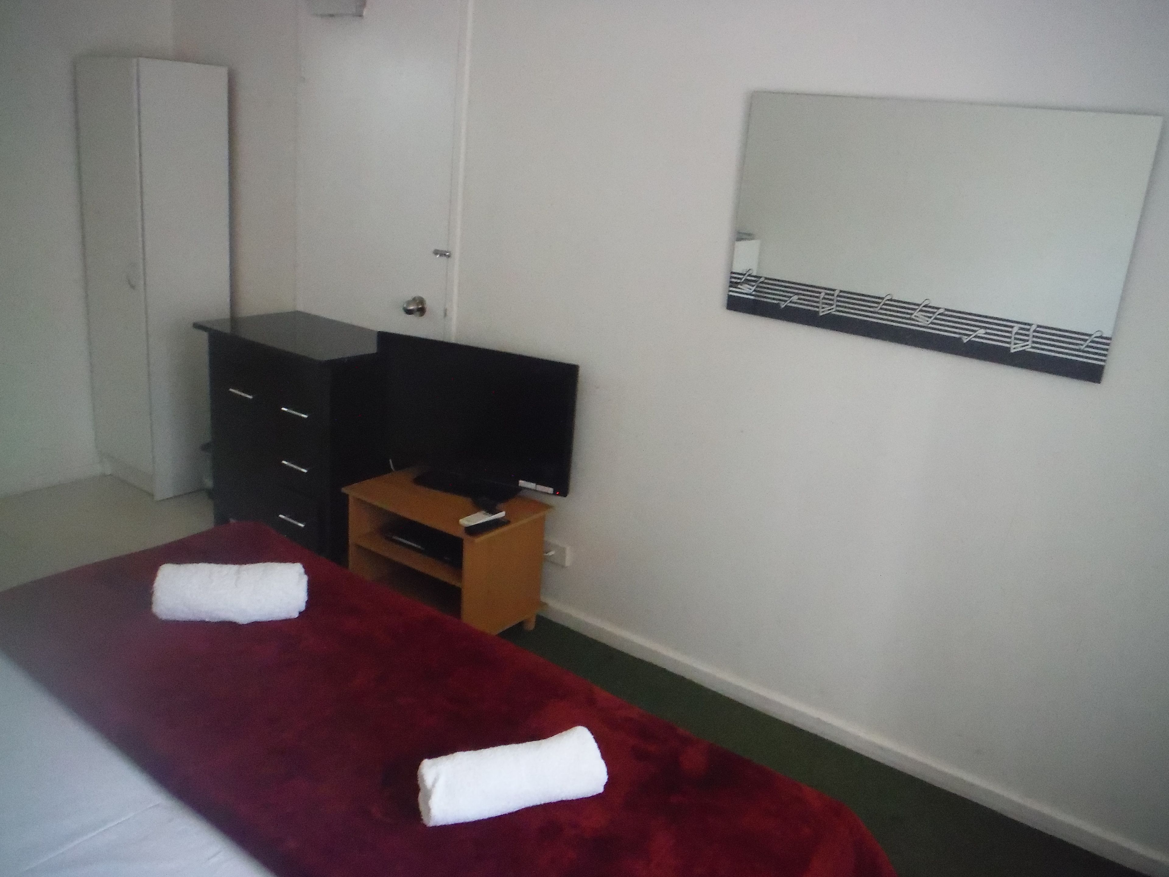 Habitación de hotel con cama, televisor, armario y espejo.