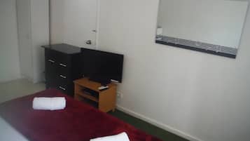 Habitación de hotel con cama, televisor, armario y espejo.