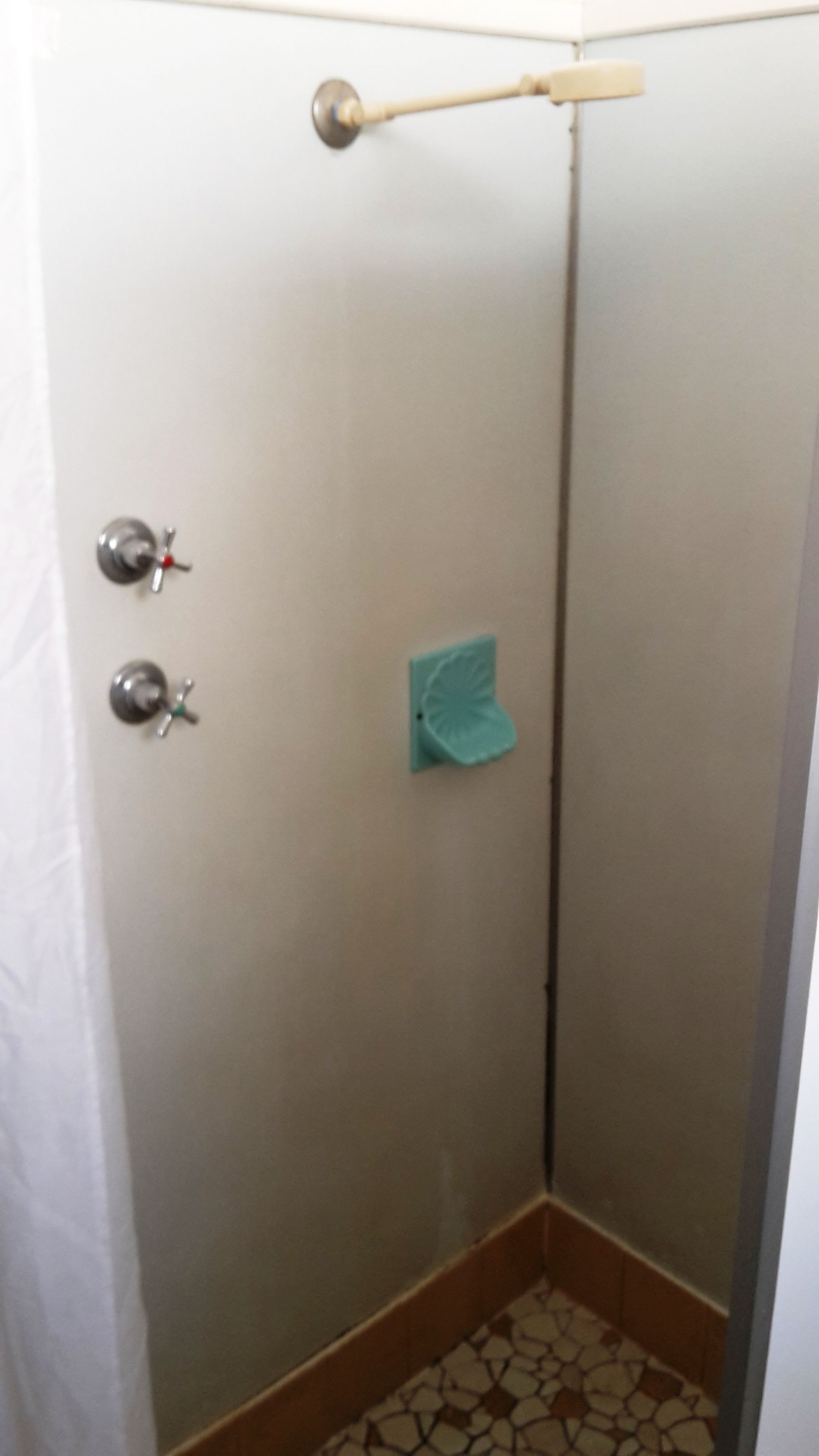 Un baño con ducha, toallero y retrete.