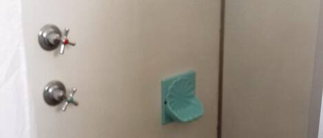 Un baño con ducha, toallero y retrete.