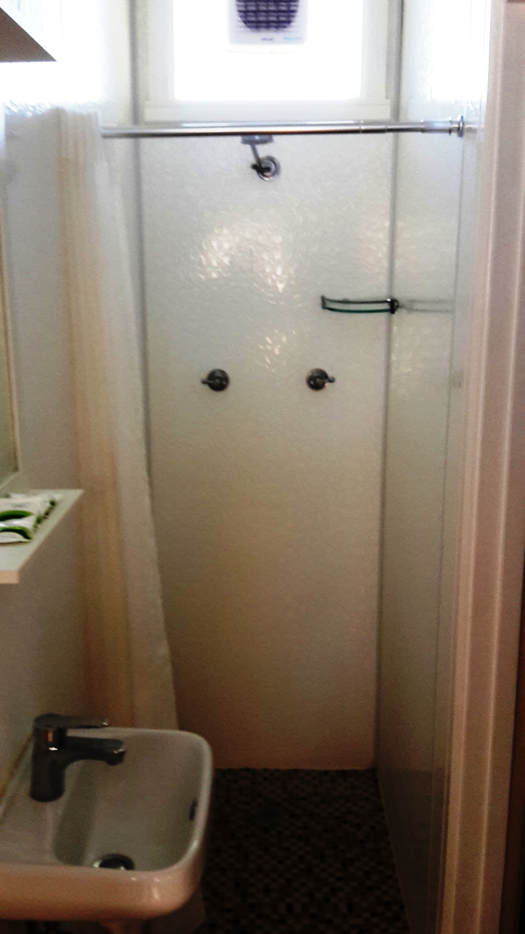 A small, narrow bathroom with a toilet, sink, and a shower area.