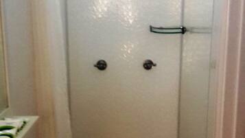 A small, narrow bathroom with a toilet, sink, and a shower area.
