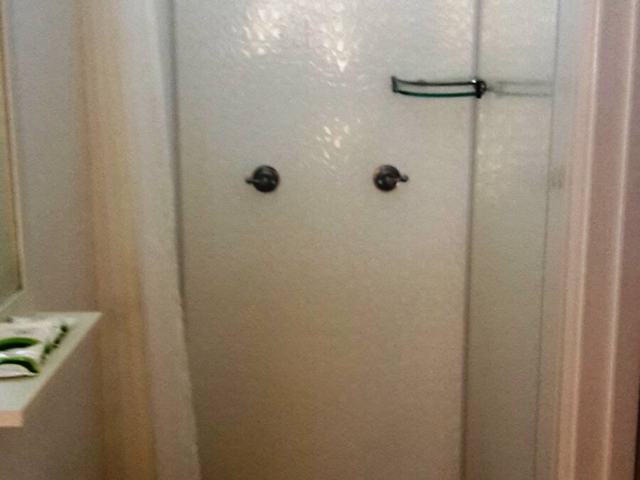 A small, narrow bathroom with a toilet, sink, and a shower area.