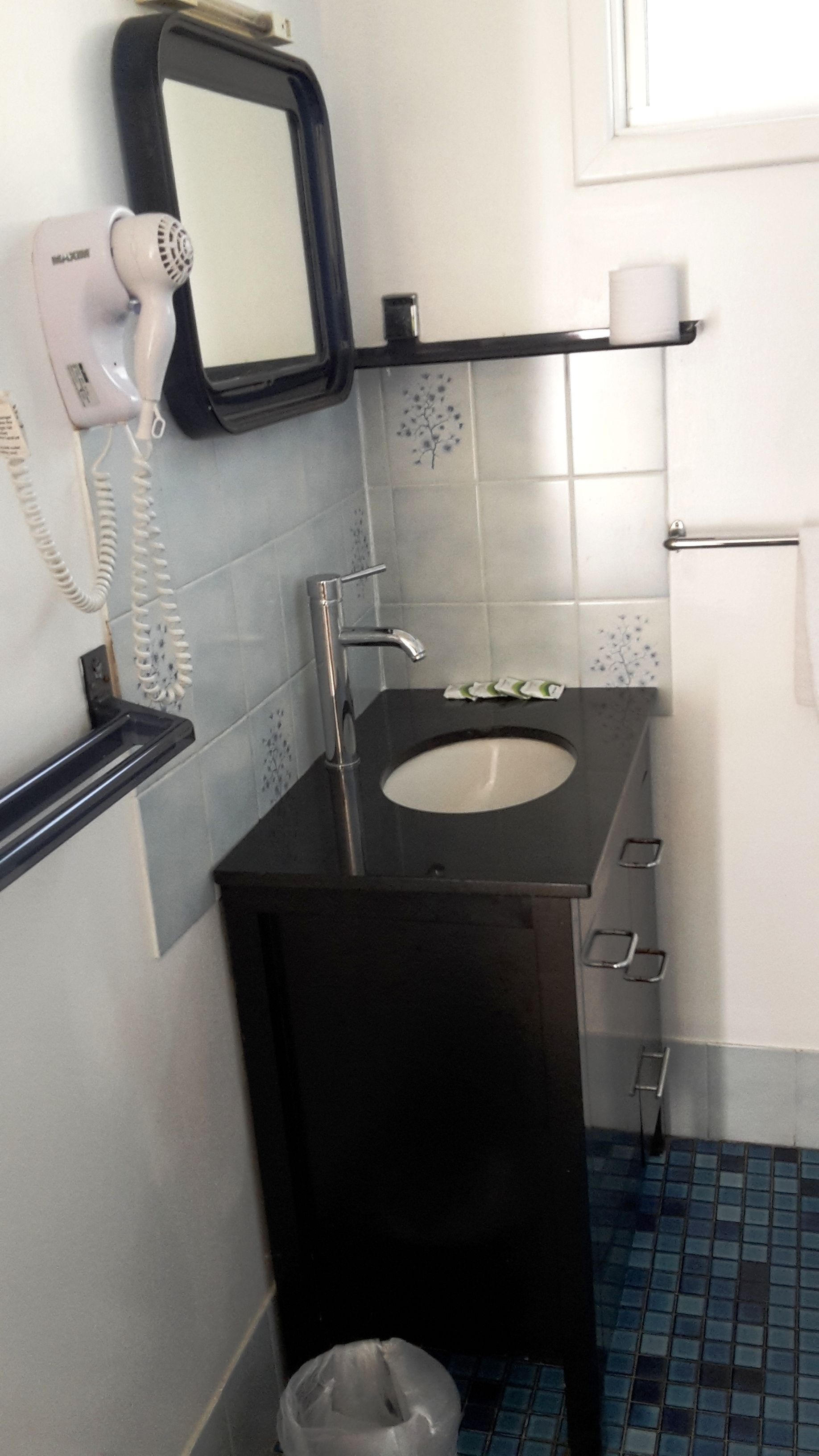 A bathroom with a black sink, a hairdryer, and a mirror.