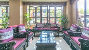 A traditional-style seating area with ornate furniture and a glass coffee table, surrounded by large windows offering views of the outdoors. - Carpio Hotel Phuket (Wichit)