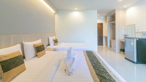 A hotel room with two beds, a wardrobe, a refrigerator, and a bathroom visible in the background. - Carpio Hotel Phuket (Wichit)