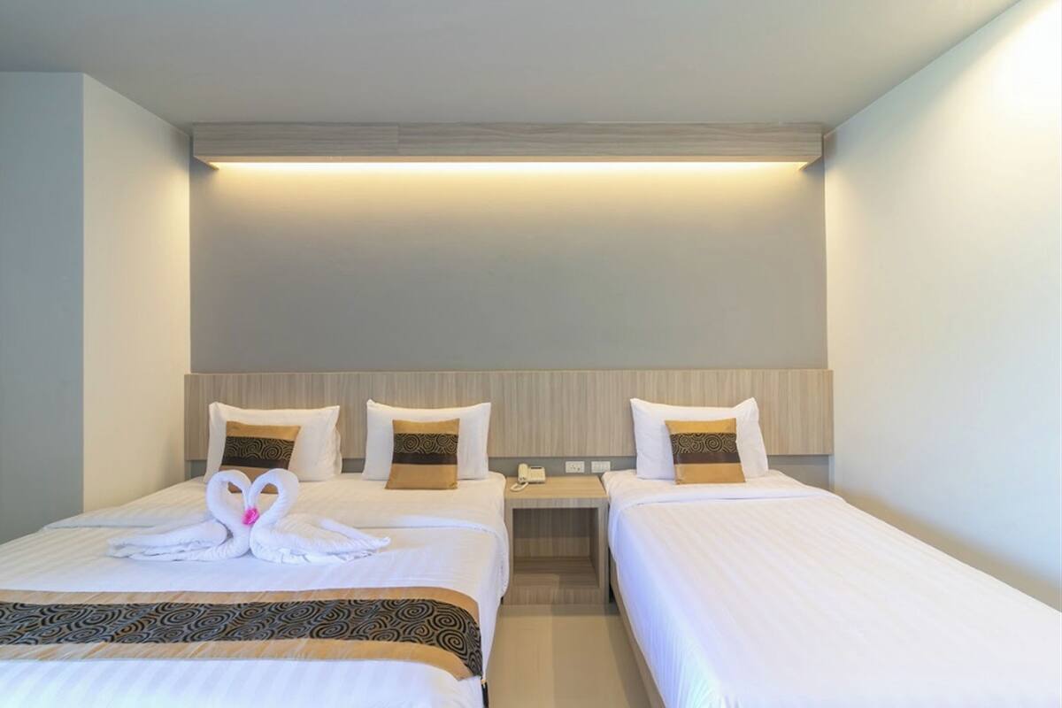 A hotel room with two beds, each with a headboard, a bedside table, and a lamp.