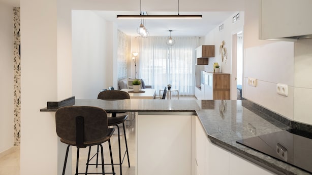 A modern kitchen with a central island, bar stools, pendant lighting, and a view into the dining area. - Apartment with sea view, parking, wifi (Marbella)
