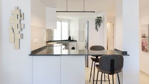 A modern kitchen with a central island, a hanging plant, and a dining area with a bar stool. - Apartment with sea view, parking, wifi (Marbella)