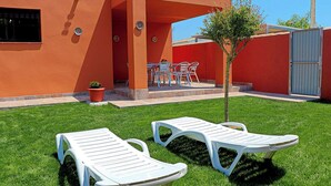 A patio with two white lounge chairs, a small tree, and a table with chairs. - Villa with private pool and Wi-Fi (CONIL DE LA FRONTERA)