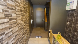 A hallway with a wooden wall, a reception desk, and a door at the end. - Japaning Kyoto (Kyoto)