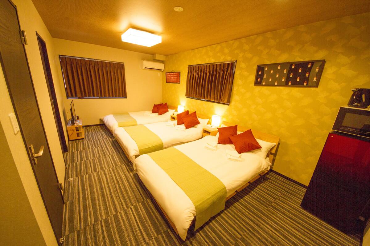 A hotel room with two beds, a desk, and a small kitchenette.