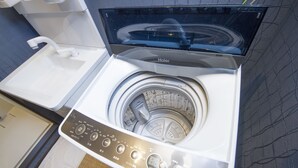 A modern, compact washer and dryer unit with a digital control panel, located in a small laundry room with a wooden floor and a tiled backsplash. - Japaning Kyoto (Kyoto)