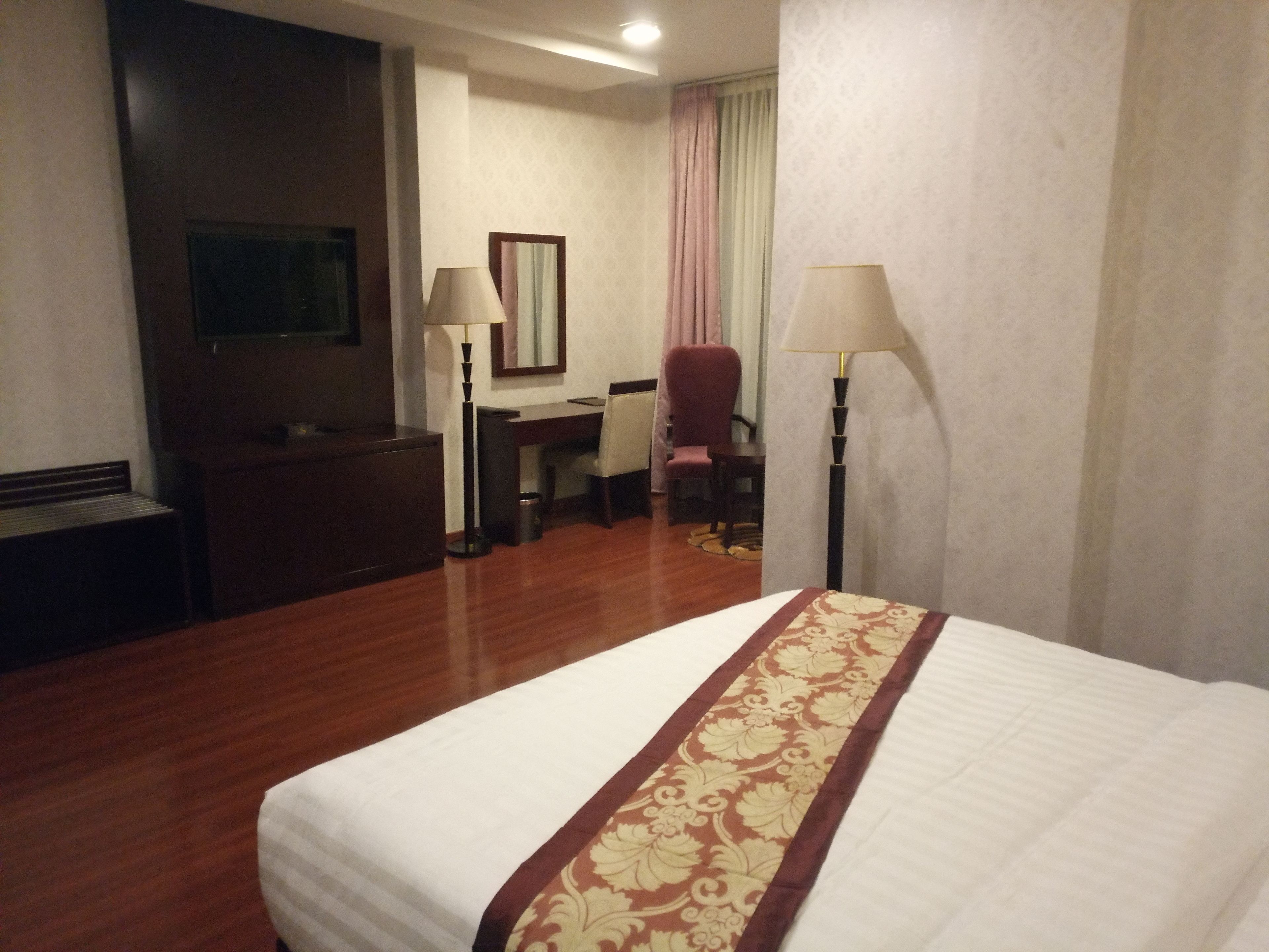 Une chambre d’hôtel équipée d’un lit, d’un bureau, d’une chaise et de deux lampes.
