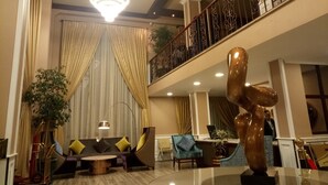 A spacious lobby with a high ceiling, a chandelier, a staircase with ornate railings, and a large abstract sculpture. - Sherar Addis Hotel (Addis Ababa)