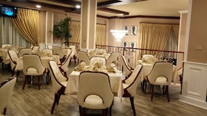 A banquet hall with multiple round tables, each set with white tablecloths and chairs, and a large chandelier hanging from the ceiling. - Sherar Addis Hotel (Addis Ababa)