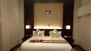 A hotel room with a large bed, two bedside lamps, a headboard with a decorative panel, and a small painting above the headboard. - Sherar Addis Hotel (Addis Ababa)