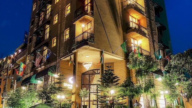 A multi-story hotel with balconies, a well-lit entrance, and outdoor seating areas. - Sherar Addis Hotel (Addis Ababa)