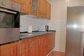 Efficient kitchen with a gas stove, microwave, and refrigerator, featuring a granite countertop and subway tiles.