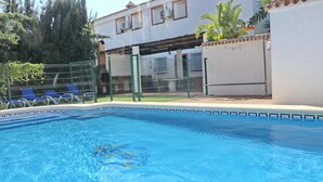 A swimming pool with clear blue water, surrounded by a fence and blue lounge chairs. - Villa with private pool and Wi-Fi (CONIL DE LA FRONTERA)