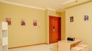 Une pièce avec une porte en bois, une petite table et deux tabourets, ainsi que trois tableaux encadrés accrochés au mur.