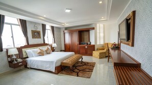 Habitación de hotel con una cama grande, un banco de madera, un televisor y un escritorio con una silla.