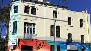 A building with a colorful mural, a 'Secret Garden' sign, and a 'One Way' sign. - Secret Garden Backpackers (Redfern)