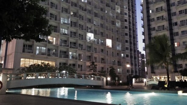 A high-rise residential building with multiple balconies, a swimming pool, and a bridge. - Haven Suite at Jazz (Makati)