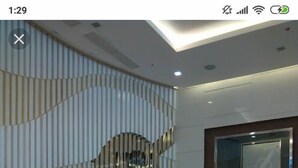 A modern reception area with a glass partition, a reception desk, and a decorative wall with vertical lines. - Haven Suite at Jazz (Makati)