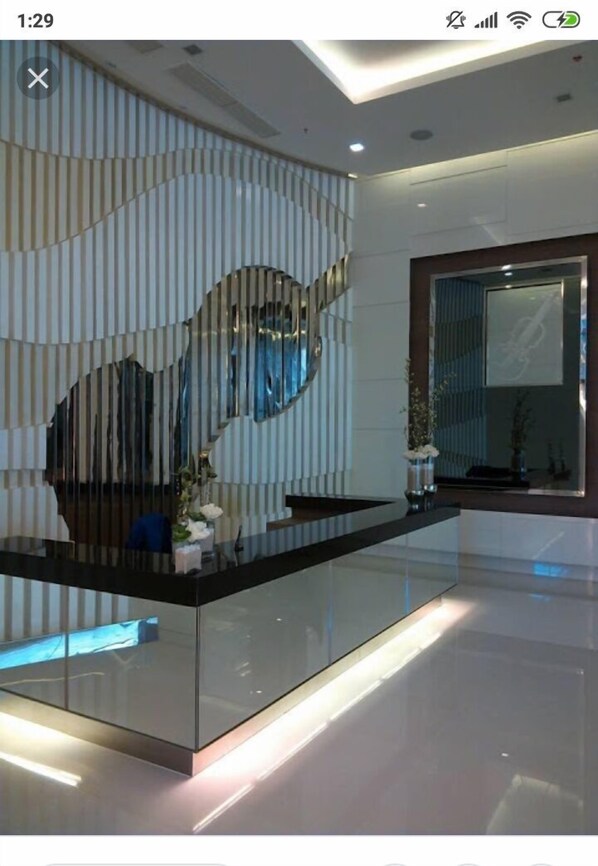 A modern reception area with a glass partition, a reception desk, and a decorative wall with vertical lines.