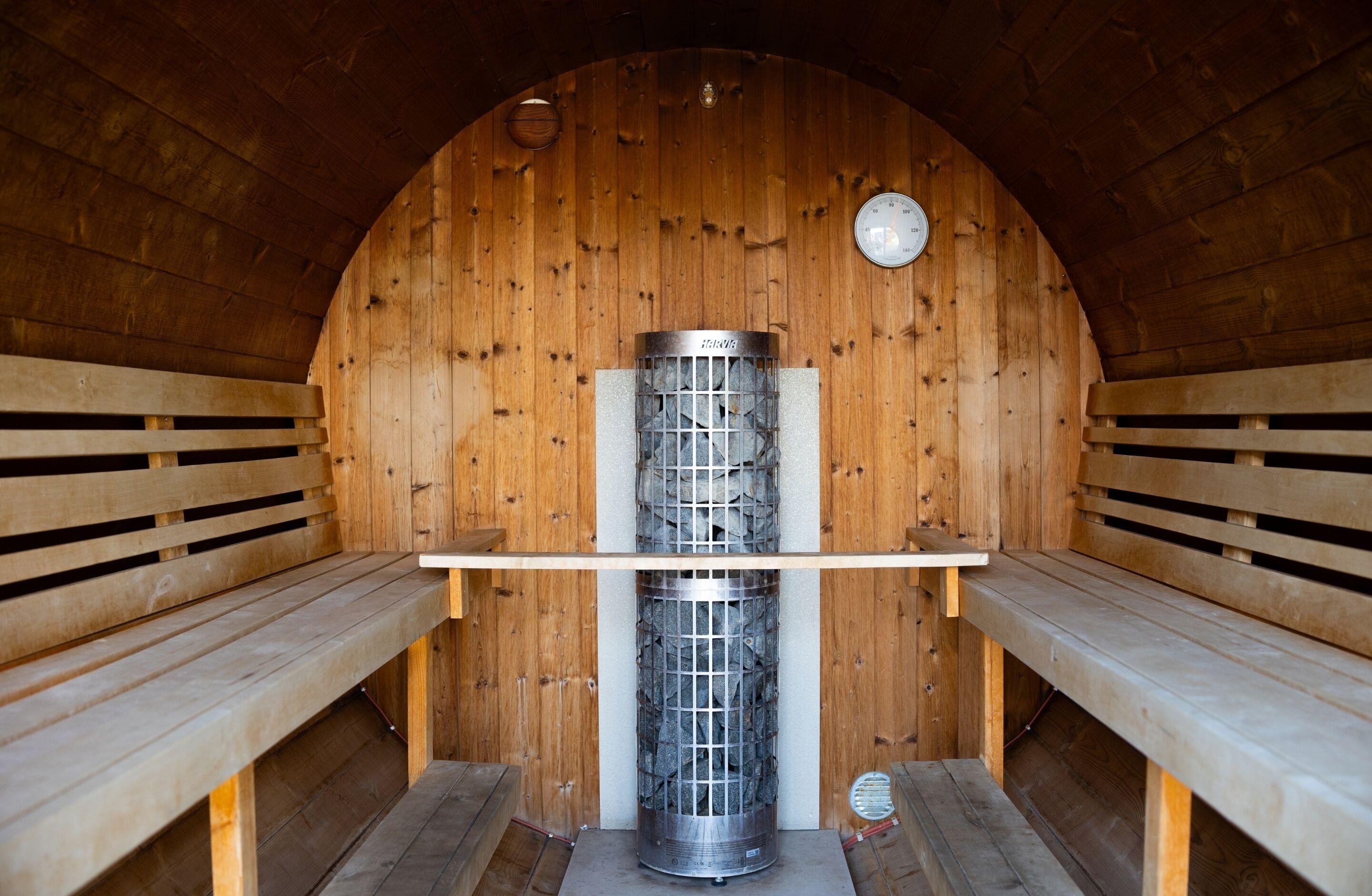 A sauna with wooden benches and a central heating unit.