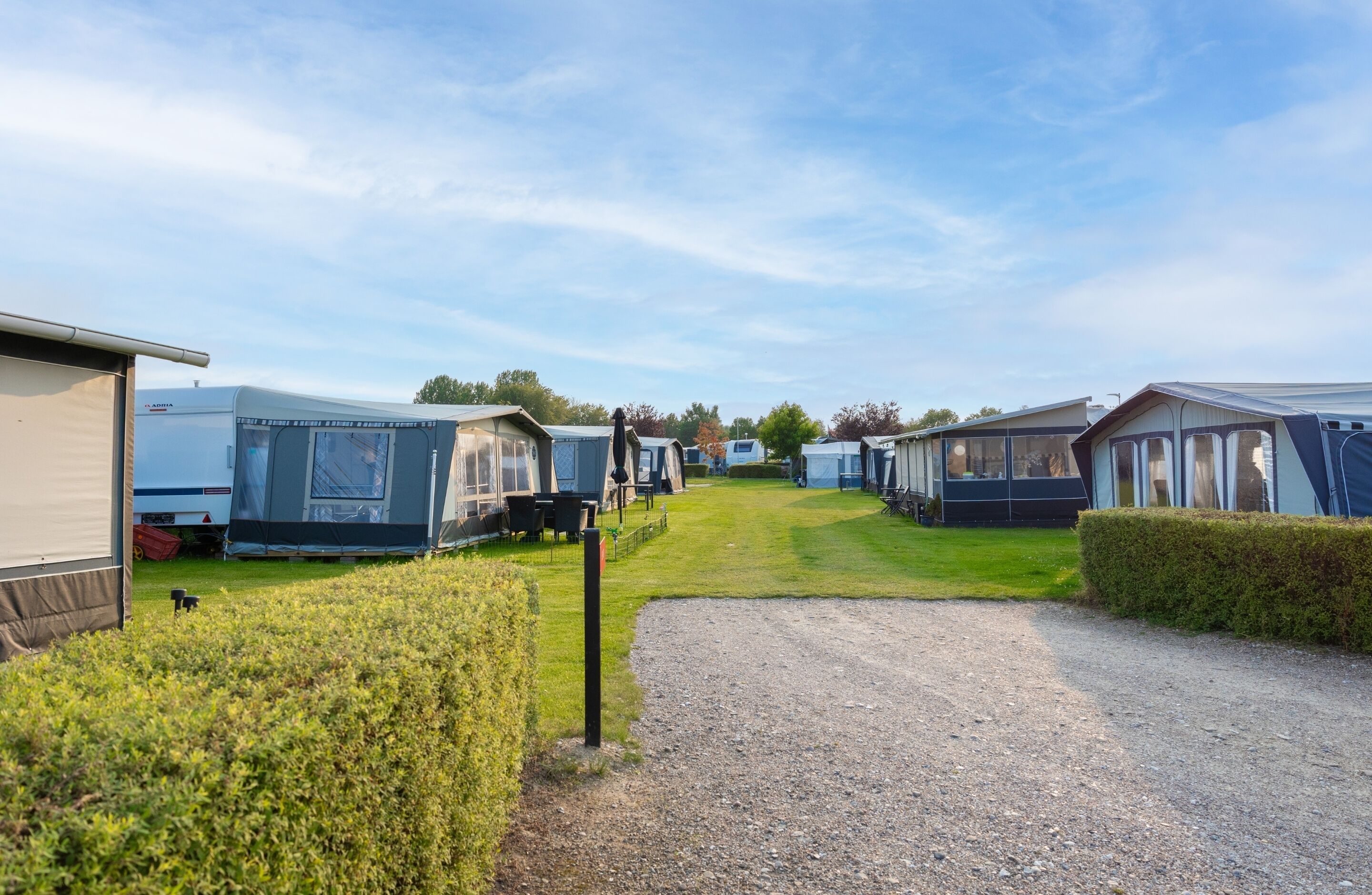 A caravan park with multiple caravans and a gravel path leading through the area.