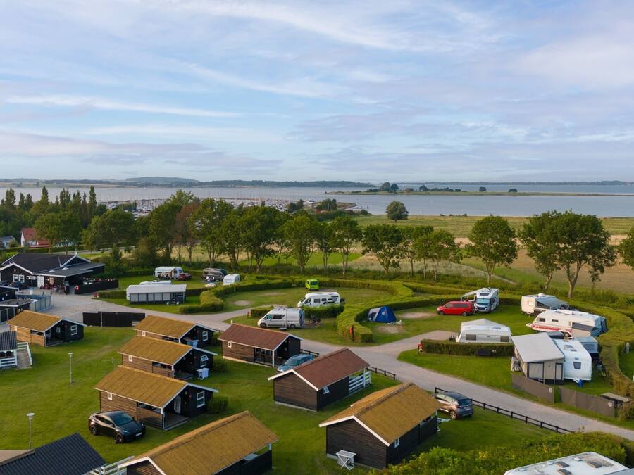 A campsite with RVs and mobile homes, a parking area, and a view of a lake.