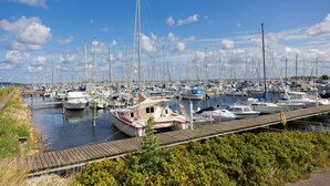 A marina with numerous boats docked, wooden walkways, and a clear blue sky. - First Camp Holbæk Fjord (Holbaek)